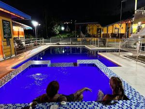 dos personas sentadas en una piscina por la noche en Ecohotel Guaduales Pereira en Pereira