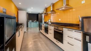 uma grande cozinha com paredes amarelas e electrodomésticos de aço inoxidável em Hostellicious em Faro
