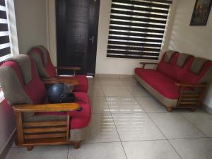 una sala de estar con 2 sofás rojos y una ventana en Alora vrindhavan villa, en Meppādi