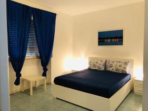 a bedroom with a bed with blue curtains and a window at Villa Mirante - Maruggio in Maruggio