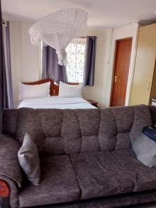 a couch in a room with a bed and a window at Best suites ngara in Nairobi
