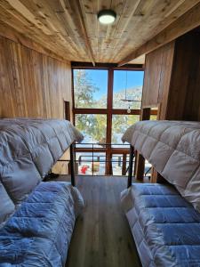 two beds in a room with a large window at Lodge Rincon del Bosque, Malalcahuello in Malalcahuello