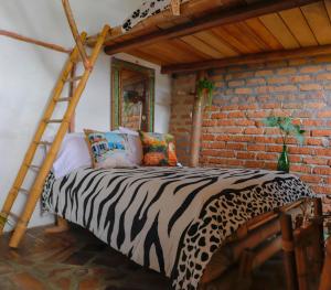 Bett in einem Zimmer mit Ziegelwand in der Unterkunft Hotel Casa Tarzan in San Agustín