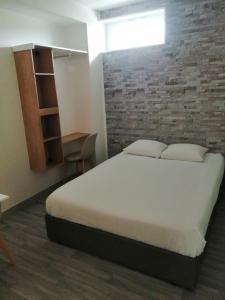 1 dormitorio con cama y pared de ladrillo en APPARTEL 76 CHAMBRES, en Rouxmesnil-Bouteilles