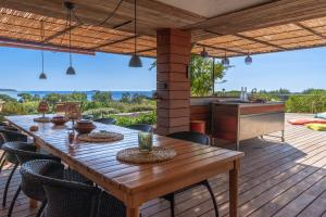 a wooden table and chairs on a deck with a kitchen at Les Bergeries De Palombaggia in Porto-Vecchio