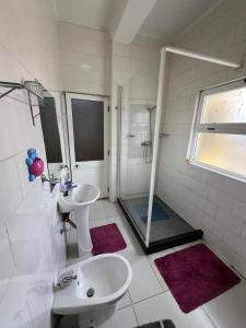 ein weißes Bad mit einem Waschbecken und einer Dusche in der Unterkunft J´S Place in Lubango