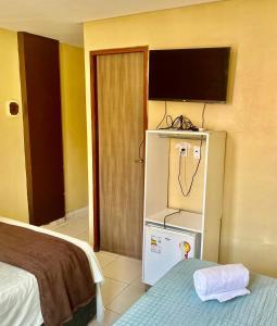 a room with a refrigerator and a tv on a wall at Hotel Santiago Juazeiro in Juazeiro do Norte