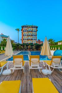 un grupo de sillas y sombrillas junto a una piscina en DE MARE FAMILY Hotel en Konaklı