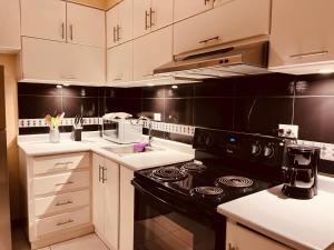 uma cozinha com armários brancos e um forno de fogão preto em Apartamentos Carmela # 3 em Siguatepeque
