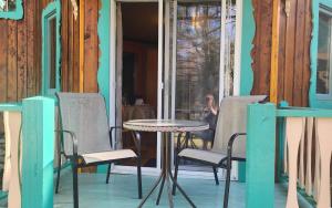 - une table et des chaises sur la terrasse couverte d'une maison dans l'établissement Domaine Rivière Sacacomie, à Saint-Alexis-des-Monts