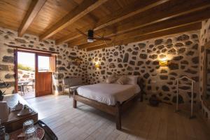 1 dormitorio con 1 cama en una habitación con paredes de piedra en Hotel Rural El Cabo de "Casa Marcos", en Villaverde