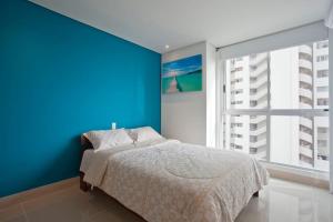 Dormitorio azul con cama y ventana grande en MURANO ELITE LUXURY OCEANFRONT BOCAGRANDE., en Cartagena de Indias