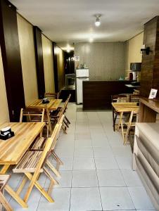 a dining room with wooden tables and a kitchen at Hotel Santiago Juazeiro in Juazeiro do Norte