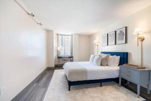 ein Schlafzimmer mit einem Bett mit einem blauen Nachttisch und zwei Fenstern in der Unterkunft Hartford Heights Skyline Views Await in Hartford