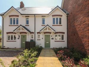 a white house with green doors and a brick wall at Waterston Cottage in Wareham