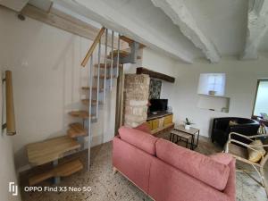 a living room with a pink couch and a staircase at Gîte Les Placettes in Sainte-Foy-de-Longas