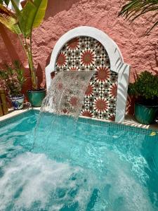 a fountain in a swimming pool next to a pink wall at Casa Limonero in Sedella
