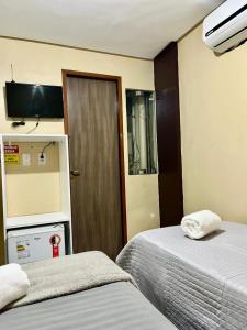 a hotel room with two beds and a door at Hotel Santiago Juazeiro in Juazeiro do Norte