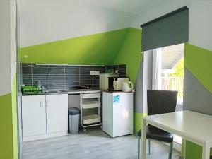 a kitchen with green and white walls and a table at Kikapcs apartman in Alsóörs