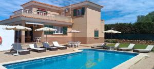 a house and a swimming pool with chairs and umbrellas at Villa Sirena in Cala en Blanes
