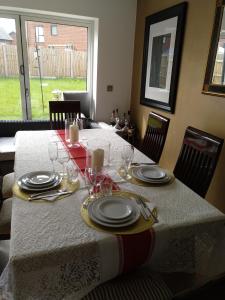 una mesa de comedor con platos y vasos. en House Rose 1 en Prescot