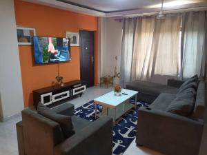 Il comprend un salon avec des canapés et une télévision à écran plat. dans l'établissement Sarah apartment B4R, à Ogbojo