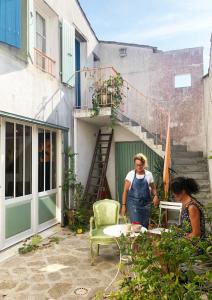a woman standing in a garden with a man at Logement Design à Loix-en-Ré - 2 étoiles - Centre Village in Loix