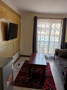 a living room with a table and a couch and a television at Best suites ngara in Nairobi