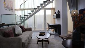 een woonkamer met een bank en een tafel bij Aurora Your 2BR Duplex Transit Apartment in Abu Dhabi
