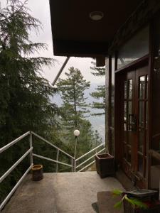 a balcony of a house with a view of the forest at Sikandar Bagh Cottages in Nathia Gali