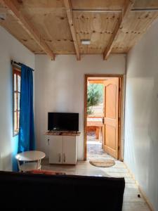 sala de estar con TV, mesa y puerta en Cabañas Ocean Forest, en El Tabo