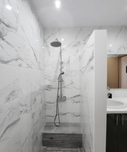 uma casa de banho em mármore branco com um chuveiro e um lavatório. em Loft Apartment in Kos em Kefalos