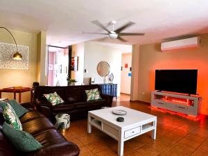 sala de estar con sofá y TV de pantalla plana en 3 BR Villa Tranquilidad, en Vega Alta