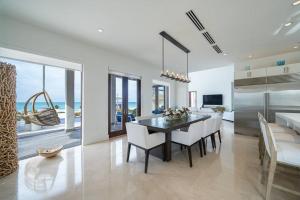 The Bahamas Beachfront Dream Villa في أليس تاون: مطبخ وغرفة طعام مع طاولة وكراسي