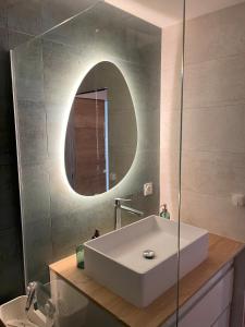 un bagno con un lavandino bianco e uno specchio di Bord de mer: soleil, plage et grande terrasse pour instants de détente (Wifi, clim) a La Grande-Motte