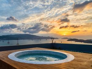 a hot tub on a deck with a sunset in the background at Venity Villa Nha Trang in Nha Trang