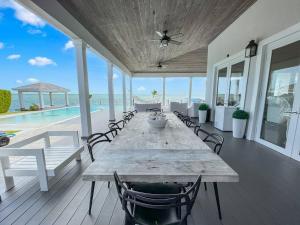 une grande table et des chaises en bois sur une terrasse donnant sur l'océan. dans l'établissement Largest Private Island Home & Pool Villa, à Alice Town