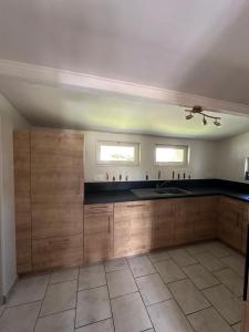 a large kitchen with wooden cabinets and two windows at Camping De La Seine in Jumièges