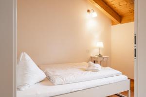 巴德小基希海姆的住宿－Haus Ahornweg，一间卧室配有一张带白色床单和一盏灯的床。