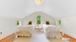 2 Betten in einem Zimmer mit weißen Wänden und Fenstern in der Unterkunft Douglas Farm House in Douglas