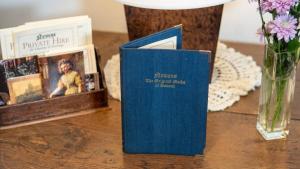 una mesa con dos libros y un jarrón con flores en Maids Guest Rooms en Kew