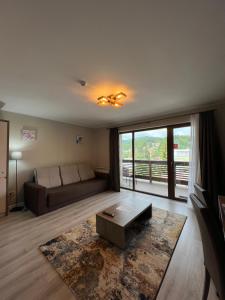 sala de estar con sofá y ventana grande en Apartamente de inchiriat- Garden Apart Predeal en Predeal