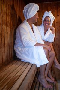 een man en vrouw op een bankje in een sauna bij Hotel Sørup Herregaard in Ringsted