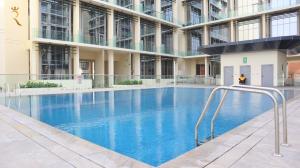 a large building with a large blue swimming pool at Aurora Your 2BR Duplex Transit Apartment in Abu Dhabi