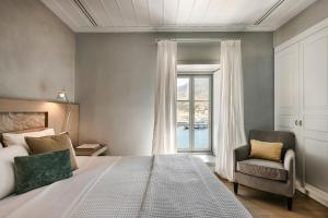 een slaapkamer met een bed, een stoel en een raam bij Hydrea Exclusive Hospitality in Hydra