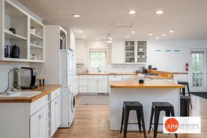 a kitchen with white cabinets and a kitchen island with stools at Tate House in Saugatuck