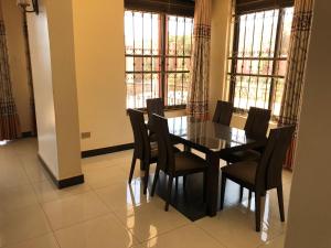 Marina Lake View Apartments,Jinja في جينجا: غرفة طعام مع طاولة وكراسي ونوافذ