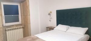1 dormitorio con cama blanca y ventana en Casa Cal da Rosins, en Muxía