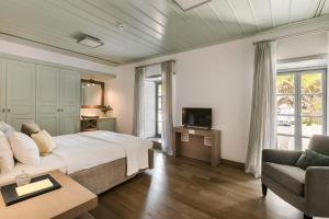 1 dormitorio con cama, sofá y TV en Hydrea Exclusive Hospitality en Hydra