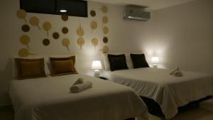 um quarto com 2 camas e 2 candeeiros na parede em Park View Hostel & Suites em Manta